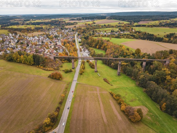 Country road crosses under a bridge in an autumn landscape with fields and villages, Dornstetten, Freudenstadt district, Germany