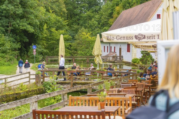 People relax in a café with a view of walkers in the countryside, Wimsener Höhle, Hayingen, Germany