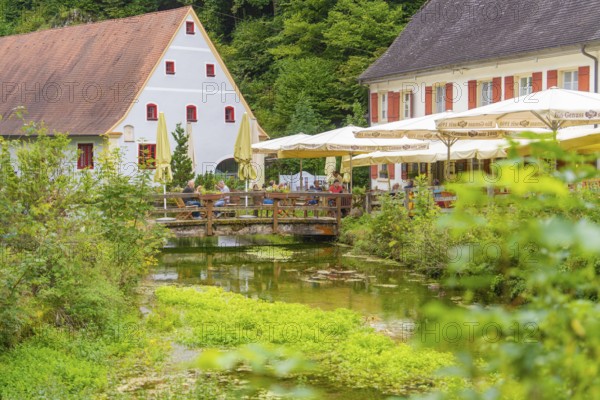Café by a stream in a quiet, green area with traditional houses, Wimsener Höhle, Hayingen, Germany
