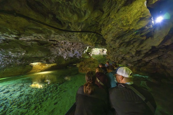 Group on a boat expedition exploring the fascinating waterways in a cave, Wimsener Höhle, Hayingen, Germany