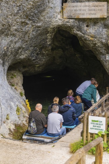 People sit on boats in front of a cave and prepare to enter, Wimsener Höhle, Hayingen, Germany