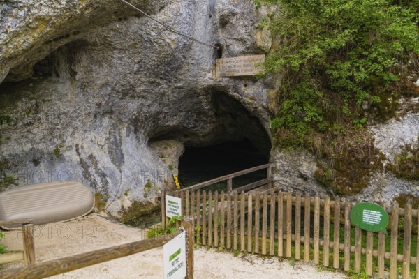 Wooden fence in front of the dark entrance of a cave in a rocky environment, Wimsener Höhle, Hayingen, Germany
