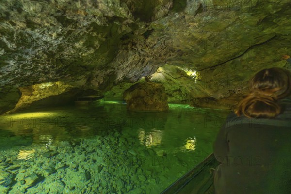 Interior of a cave with green water and rocks, people exploring the underground body of water, Wimsener Höhle, Hayingen, Germany