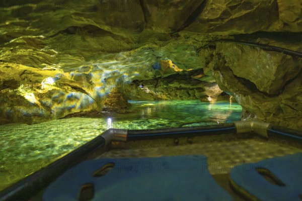 View from a boat of the impressively illuminated interior of a cave with running water, Wimsener Höhle, Hayingen, Germany