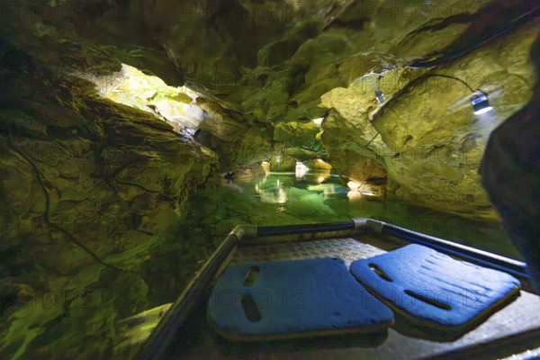 Exploration boat within a cave with fascinating green water and rock formations, Wimsener Höhle, Hayingen, Germany