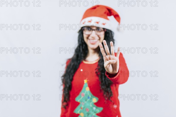Happy girl in Christmas hat counting number FOUR, isolated. Smiling girl in Christmas sweater counting number 4