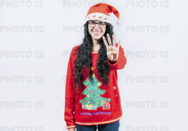 Smiling girl in Christmas sweater counting number 4. Happy girl in Christmas hat counting number FOUR, isolated