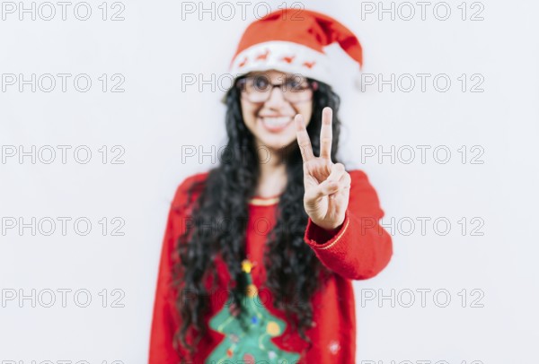 Happy girl in Christmas hat counting number TWO, isolated. Smiling girl in Christmas sweater counting number 2