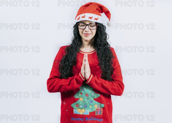 Hopeful Young woman in Christmas sweater making a wish, isolated. Hopeful girl in Christmas hat making a wish isolated