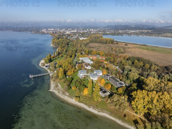 Aerial view of the Mettnau peninsula, surrounded by autumn vegetation, in western Lake Constance with the spa center, Mettnaukur, boat dock and restaurant Strandcafe, Radolfzell, Konstanz district, Baden-Württemberg, Germany