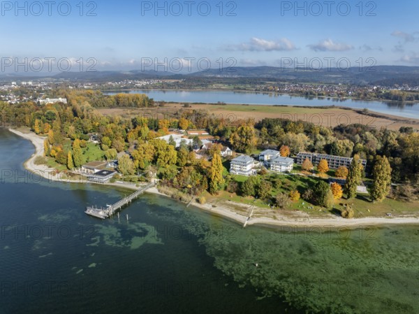 Aerial view of the Mettnau peninsula, surrounded by autumn vegetation, in western Lake Constance with the spa center, Mettnaukur, boat dock and restaurant Strandcafe, on the horizon of Bodanrück, in front of Markelfinger Winkel with the villages of Markelfingen and Güttingen, Radolfzell, Konstanz district, Baden-Württemberg, Germany