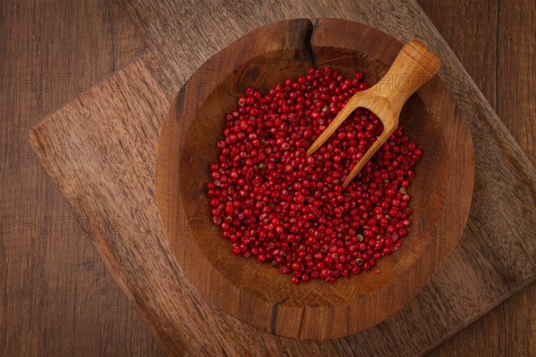 Bright red peppercorns, in a wooden bowl, with a small wooden tray