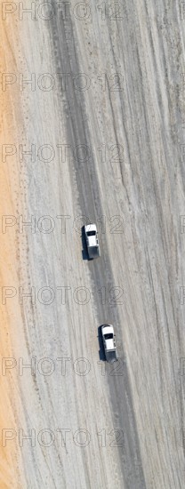 Aerial view, top-down view, two off-road cars driving on a road in arid countryside, Botswana