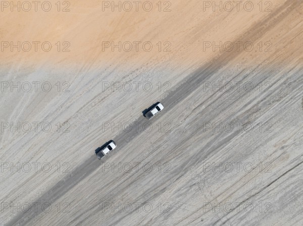 Aerial view, top-down view, two off-road cars driving on a road in arid countryside, Botswana