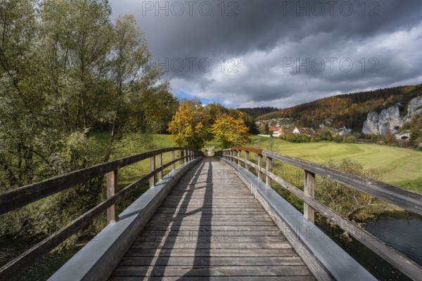 Wooden bridge across the Danube to Käppeler Manor with St. George's Basilica near Thiergarten in the Upper Danube Valley, surrounded by autumn vegetation, Sigmaringen district, Baden-Württemberg, Germany