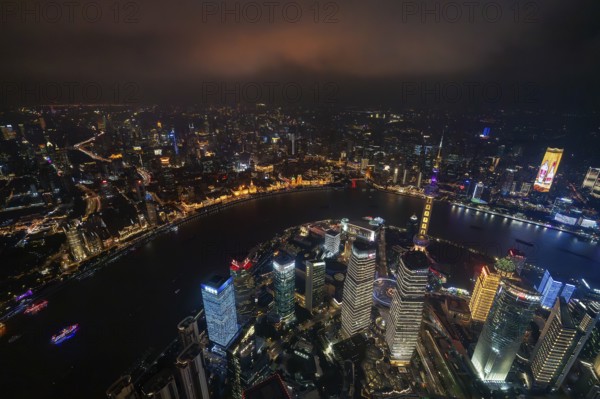 Aerial view over The Bund, Huangpu River and Lujiazui financial district with illuminated skyscrapers, in Pudong at the city Shanghai at night, China