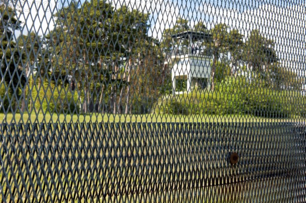 View of former area of the GDR through original GDR border fence from 1970s with death strips on former zone border between West Germany and GDR East Germany, in the background US watchtower, today open-air museum Museum Point Alpha Memorial, Rasdorf, Hesse, Geisa, Thuringia, Germany