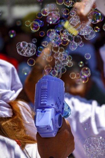 Playing with colorful soap bubble gun in sunny day