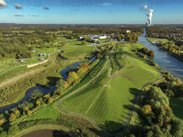Castrop-Rauxel, North Rhine-Westphalia, Germany - Autumn on the restored Emscher, EMSCHERLAND adventure park, a new nature and water adventure park on the restored Emscher, at the Emscher water cross with the Rhine-Herne Canal on the city limits of Recklinghausen and Castrop-Rauxel. A new vineyard in front. Flood protection through area expansion. The ecological focus at the confluence of the Suderwicher Bach and Emscher rivers will also be a future garden of the IGA 2027 International Garden Exhibition. Before the restoration, the river system of the Emscher was an open, aboveground waste water channel, mixed water channel with surface water and waste water. Back right, the new bridge jump over the Emscher. On the horizon the Datteln 4 power plant