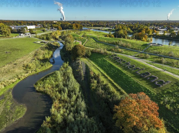 Castrop-Rauxel, North Rhine-Westphalia, Germany - Autumn on the restored Emscher, EMSCHERLAND adventure park, a new nature and water adventure park on the restored Emscher, at the Emscher water cross with the Rhine-Herne Canal on the city limits of Recklinghausen and Castrop-Rauxel. Flood protection through area expansion. The ecological focus at the confluence of the Suderwicher Bach and Emscher rivers will also be a future garden of the IGA 2027 International Garden Exhibition. Before the restoration, the river system of the Emscher was an open, aboveground waste water channel, mixed water channel with surface water and waste water. Back right, the new bridge jump over the Emscher. On the horizon the Datteln 4 power plant