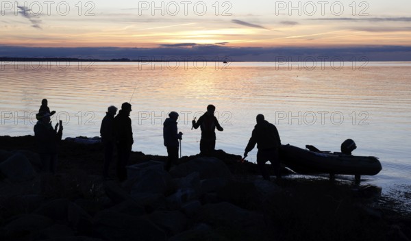 Angler on the beach during sunset, an angler docks on the shore with his inflatable boat, Fehmarn island, 18.10.2025, Fehmarn, Schleswig-Holstein, Germany