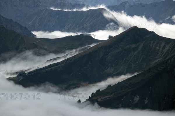 View from the Nebelhorn summit to mountains of the Allgäu Alps, in the middle of Fellhorn Horn with summit station and Kanzelwand cable car summit station, mountains rise from fog in the valley, Oberstdorf, Oberallgäu, Allgäu, Bavaria, Germany