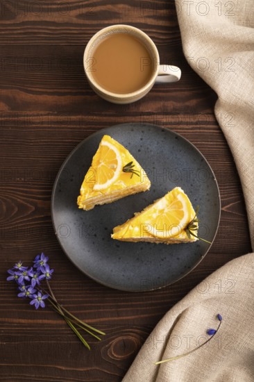 Lemon cake on brown wooden background and linen textile, cup of coffee, top view, flat lay, close up