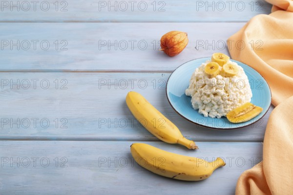 White ?ottage cheese, Curd, with Banana on blue wooden background and orange textile, side view, copy space