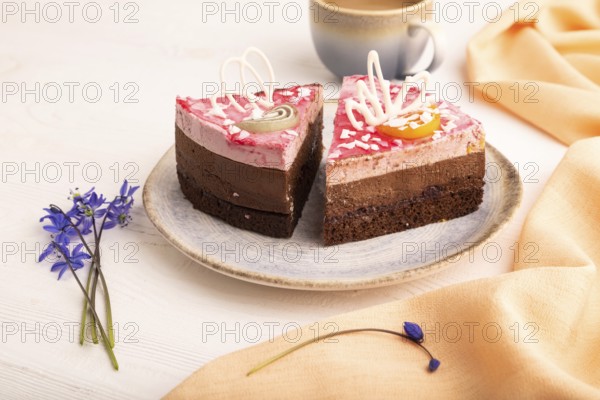 Chocolate cake on white wooden background and orange linen textile, cup of coffee, side view, close up