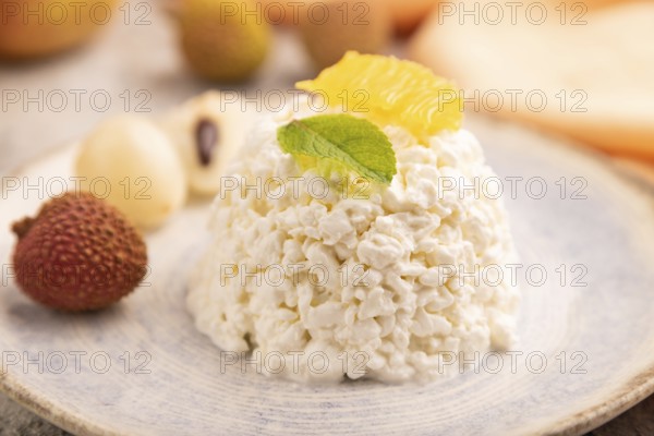 White ?ottage cheese, Curd, with orange and lychee on brown concrete background and orange textile, side view, close up, selective focus