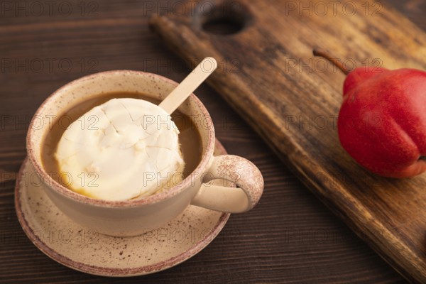 ?hocolate Ice cream in white glaze, cup of coffee, on brown wooden background, side view, close up, selective focus