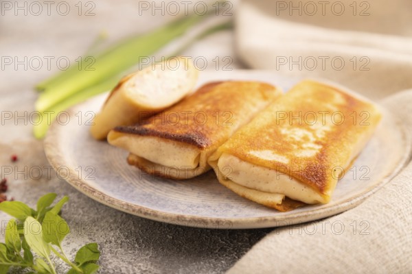 Fried crispy pancakes with meat and cheese on brown concrete background and linen textile. side view, close up, selective focus