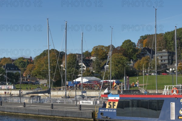 Kiel harbour, Kiellinie waterfront, Reventlou pier, restaurant, ferry, trees in autumn colors, blue sky, sunshine, Kiel Fjord, Baltic Sea, Schleswig-Holstein, Germany