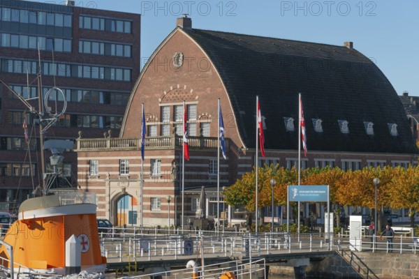 Kiel port, fishing hall shipping museum, architecture, barrel roof, brick building, flags, museum bridge with historic Hindenburg sea rescue cruiser from 1944, trees in autumn leaves, Kiel Fjord, Baltic Sea, Schleswig-Holstein, Germany