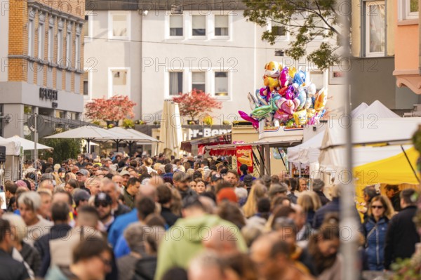Busy shopping street in autumn, people strolling between modern buildings and colorful shops, Urschelherbst street festival, Nagold, Germany