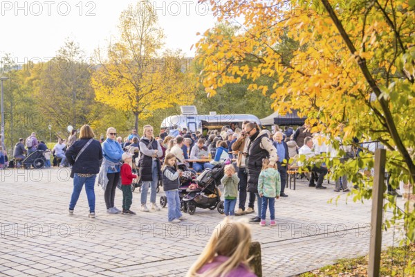 Families and children enjoy an outdoor picnic under colorful trees on an autumn day, Urschelherbst Street Festival, Nagold, Germany