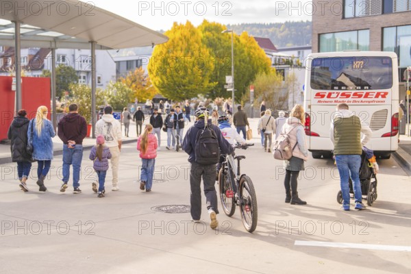 Busy scene at a bus stop, people on the move, a cyclist pushes his bike, Urschelherbst street festival, Nagold, Germany