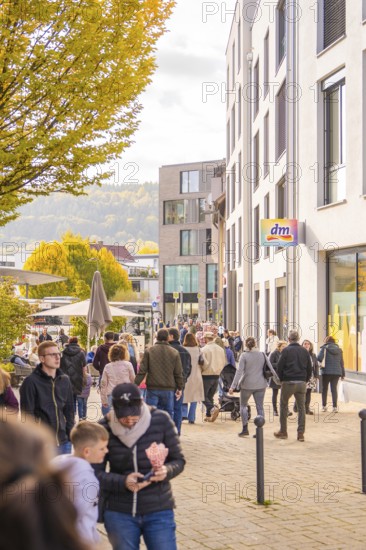 A busy street scene in a city, people walking near shops and buildings, Urschelherbst street festival, Nagold, Germany
