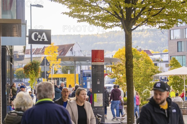 Street scene with people in a city with shops and trees in autumn leaves in the background, Urschelherbst street festival, Nagold, Germany