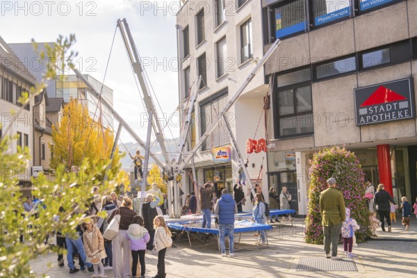 People enjoy activities on bungee trampolines in front of municipal shops and a pharmacy, Urschelherbst Street Festival, Nagold, Germany