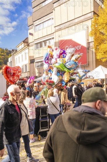 Colourful balloons over a large crowd of people on an autumn road at a happy occasion, Urschelherbst street festival, Nagold, Germany