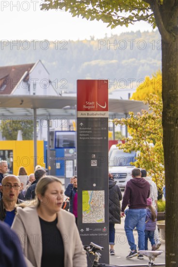 People walk past a bus stop, a signpost shows the way, Urschelherbst Street Festival, Nagold, Germany