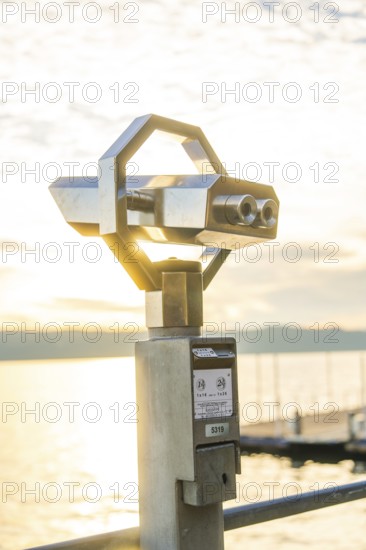 Modern metal binoculars with a view of the lake at sunrise, Überlingen, Lake Constance, Germany
