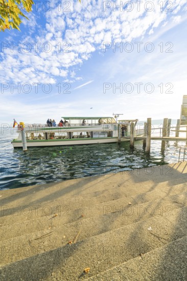 A ship is anchored at a pier on a sunny lake under a clear sky, Überlingen, Lake Constance, Germany