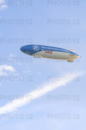 Advertising zeppelin in a clear sky with clouds in the background, Überlingen, Lake Constance, Germany