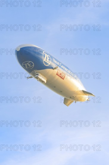 Zeppelin flies in evening light with clear sky, shows advertising message, Überlingen, Lake Constance, Germany