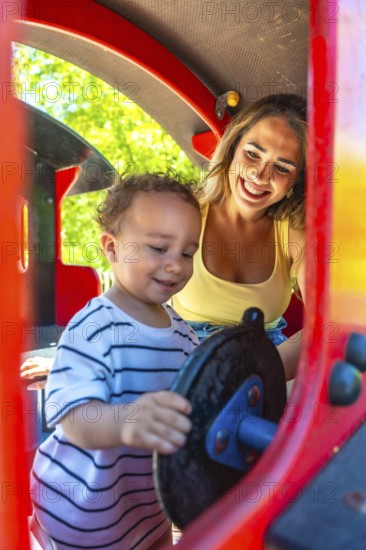 Mother and toddler having fun playing on a playground train ride, enjoying quality time together on a sunny day