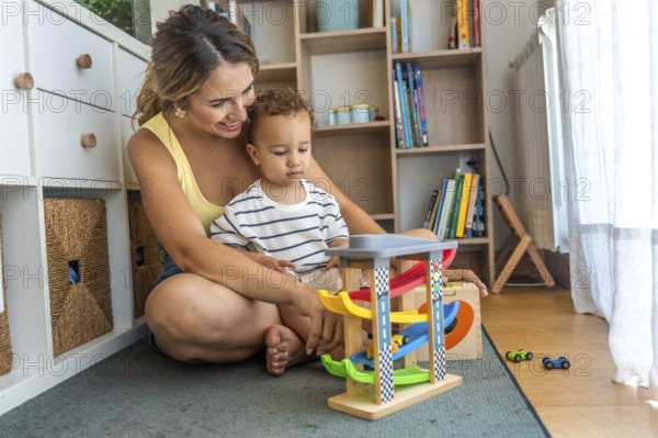 Mother and son enjoying playtime together, exploring a toy car garage in their cozy living room