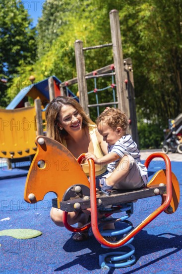 Smiling mother spending time with her baby son, enjoying a sunny day at the playground, promoting family bonding and child development