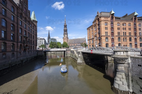 Boat on the Kleines Fleet canal with Kannengießer bridge and tower of the main church of St. Katharinen, Speicherstadt. Hamburg, Germany